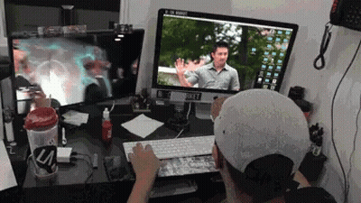 A Man Is Typing On A Keyboard In Front Of Two Computer Monitors One Of Which Says ' A ' On It GIF