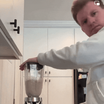 A Man Is Using A Blender In A Kitchen With A T On The Cabinet GIF