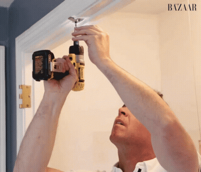 A Man Is Using A Dewalt Drill On A Door Frame GIF