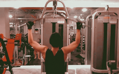 A Man Is Using A Machine In A Gym That Says Lat Pull Down GIF