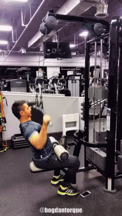 A Man Is Using A Machine In A Gym With The Words @Bogdantorque Below Him GIF