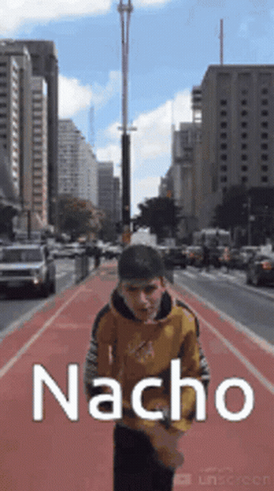 A Man Is Walking Down A City Street With The Word Nacho Written On The Side Of Him . GIF