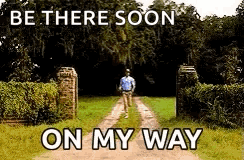 A Man Is Walking Down A Dirt Road With The Words `` Be There Soon On My Way '' Above Him . GIF