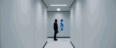 A Man Is Walking Down A Hallway With A Blue Bottle In His Hand . GIF