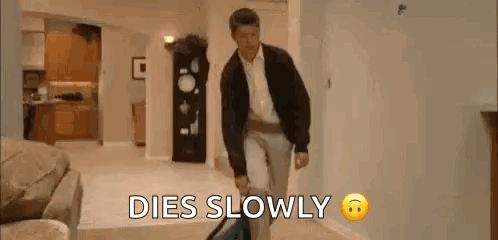 A Man Is Walking Down A Hallway With A Suitcase And The Words `` Dies Slowly '' . GIF