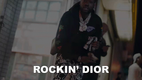 A Man Is Walking Down A Street And The Words Rockin ' Dior Are On The Bottom GIF