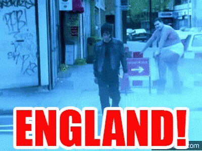 A Man Is Walking Down A Street With The Words England Written In Red GIF