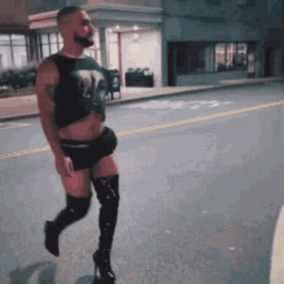 A Man Is Walking Down The Street Wearing Thigh High Boots GIF