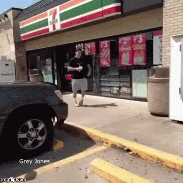 A Man Is Walking In Front Of A 7 Eleven GIF