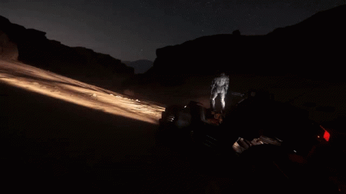 A Man Is Walking In The Dark With A Flashlight GIF