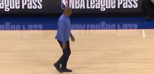 A Man Is Walking On A Basketball Court In Front Of A Nba League Pass Sign . GIF