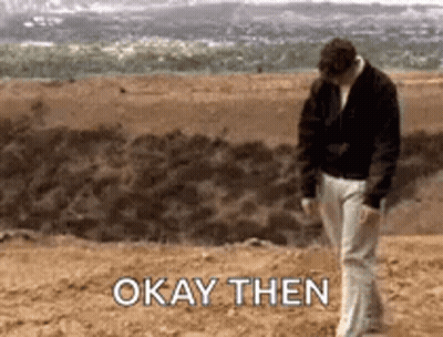 A Man Is Walking On A Dirt Field With The Words `` Okay Then '' Written On The Ground . GIF