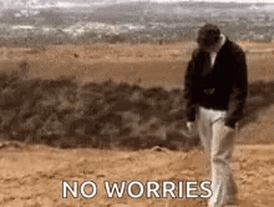 A Man Is Walking On A Dirt Road With The Words `` No Worries '' Written On The Ground . GIF