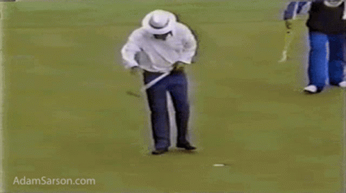 A Man Is Walking On A Golf Course Holding A Golf Club . GIF