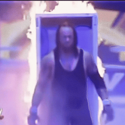A Man Is Walking Out Of A Box With Flames Coming Out Of It And Holding A Knife . GIF