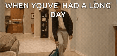 A Man Is Walking Through A Living Room Carrying A Suitcase And A Backpack . GIF