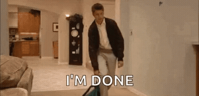 A Man Is Walking Through A Living Room Carrying A Suitcase And A Bag . GIF