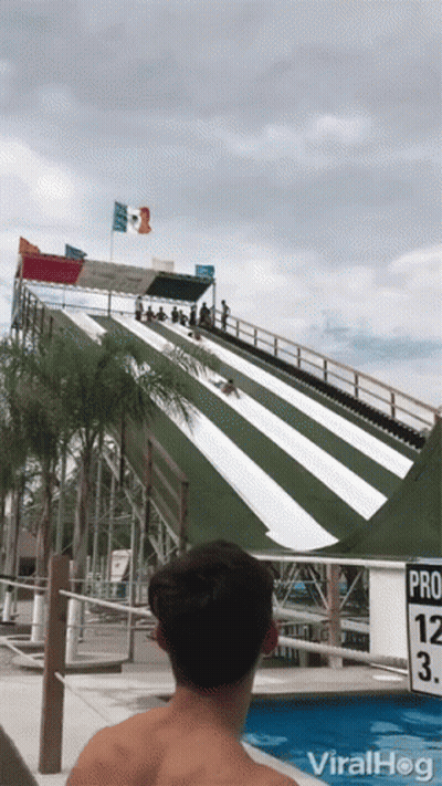 A Man Is Watching A Person Slide Down A Water Slide At A Water Park With The Words Viralhog On The Bottom GIF