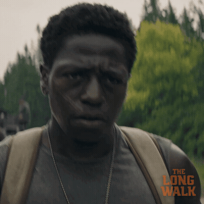 A Man Is Wearing A Backpack And A Shirt That Says The Long Walk On It GIF