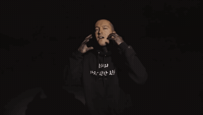 A Man Is Wearing A Black Hoodie With Korean Writing On The Front GIF