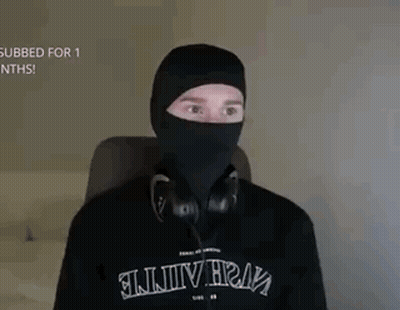 A Man Is Wearing A Black Mask And Headphones While Sitting In A Chair . GIF