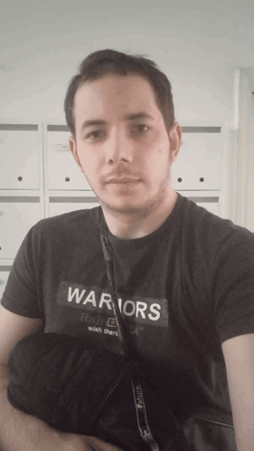 A Man Is Wearing A Black Shirt That Says Warriors On It GIF