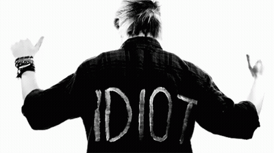 A Man Is Wearing A Black Shirt With The Word Idiot Written On It . GIF