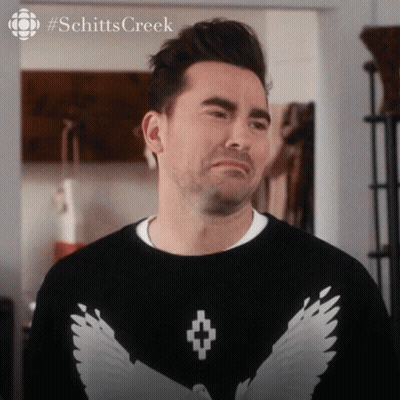 A Man Is Wearing A Black Sweater With White Wings On The Front GIF