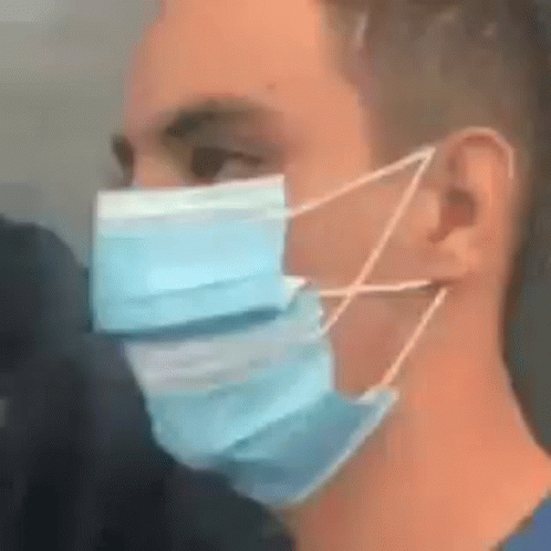 A Man Is Wearing A Blue Face Mask With A String Around His Ear . GIF