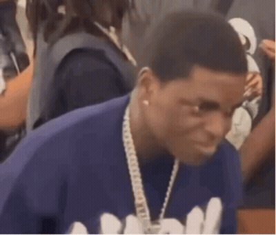 A Man Is Wearing A Blue Shirt And A Chain Around His Neck . GIF