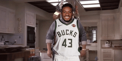 A Man Is Wearing A Bucks Jersey And Shorts GIF