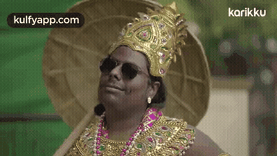 A Man Is Wearing A Crown , Sunglasses , A Necklace , And A Hat . GIF