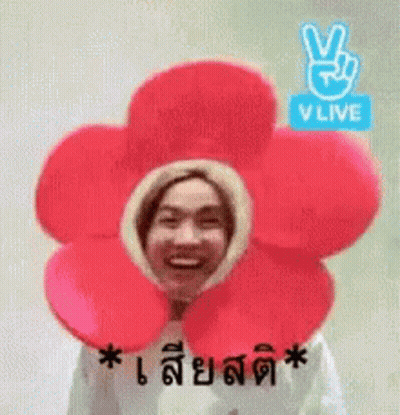 A Man Is Wearing A Flower Hat With A Peace Sign On It . GIF