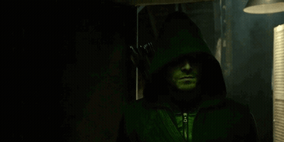 A Man Is Wearing A Green Hooded Jacket And Holding An Arrow . GIF