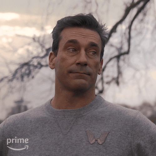A Man Is Wearing A Grey Sweater With A Pink Butterfly On The Front And The Word Prime On The Bottom GIF