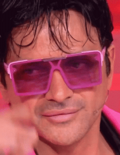 A Man Is Wearing A Pair Of Pink Sunglasses And Pointing At The Camera . GIF