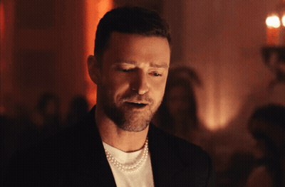 A Man Is Wearing A Pearl Necklace And A Black Jacket GIF