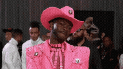 A Man Is Wearing A Pink Cowboy Hat And A Pink Jacket GIF