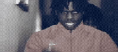A Man Is Wearing A Pink Nike Jacket And Smiling . GIF