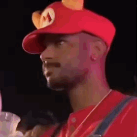 A Man Is Wearing A Red Hat With Ears On It And A Mushroom On It . GIF