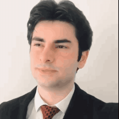 A Man Is Wearing A Suit And Tie And Looking At The Camera GIF