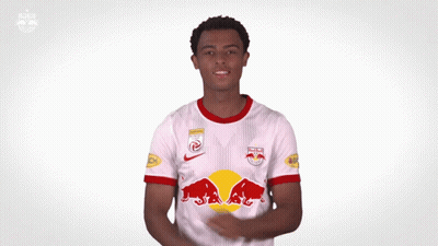 A Man Is Wearing A White Jersey With Red Bulls On The Front GIF