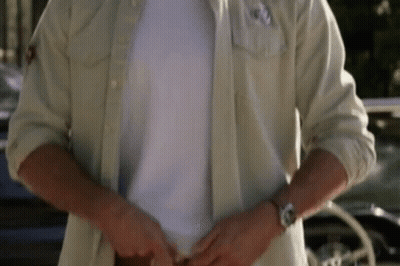 A Man Is Wearing A White Shirt And A Watch While Standing In Front Of A Car . GIF