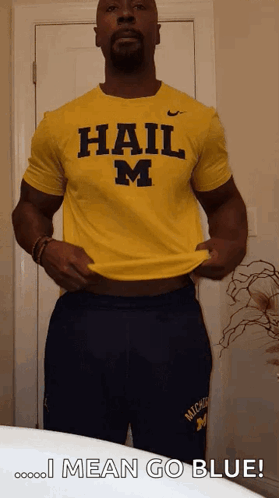 A Man Is Wearing A Yellow Shirt That Says Hail M On It GIF