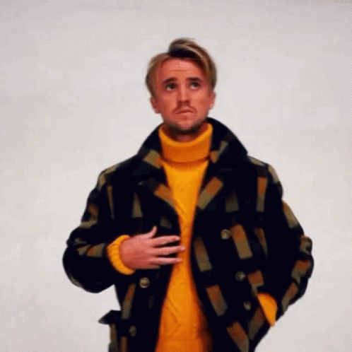 A Man Is Wearing A Yellow Turtleneck Sweater And A Plaid Jacket . GIF