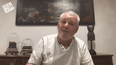 A Man Is Wearing Headphones In Front Of A Painting That Says " Good Bad Rugby " GIF