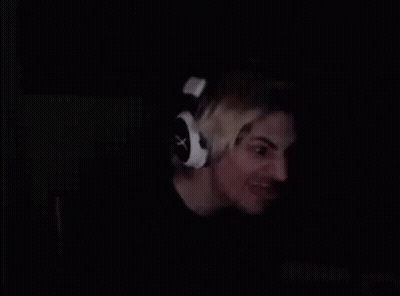A Man Is Wearing Headphones In The Dark And Smiling . GIF