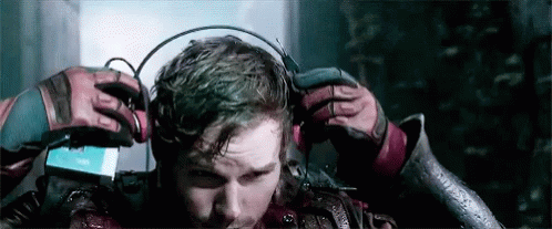A Man Is Wearing Headphones On His Head While Standing In A Dark Room . GIF