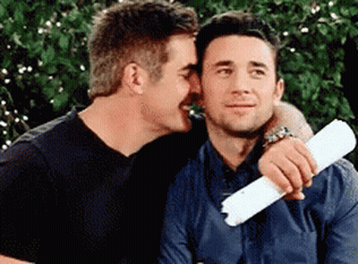 A Man Is Whispering Into Another Man 'S Ear While Holding A Piece Of Paper GIF
