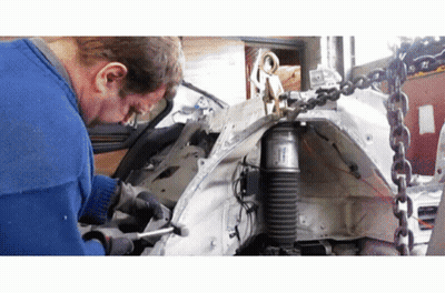 A Man Is Working On A Car With A Shock Absorber Attached To It GIF